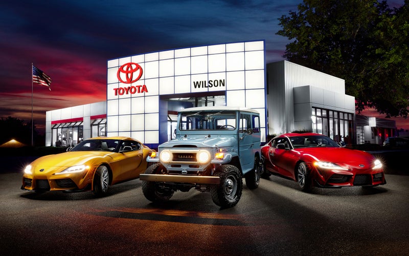 Front of dealership with yellow, blue and red vehicles and American flag in background | Wilson Toyota of Ames in Ames IA